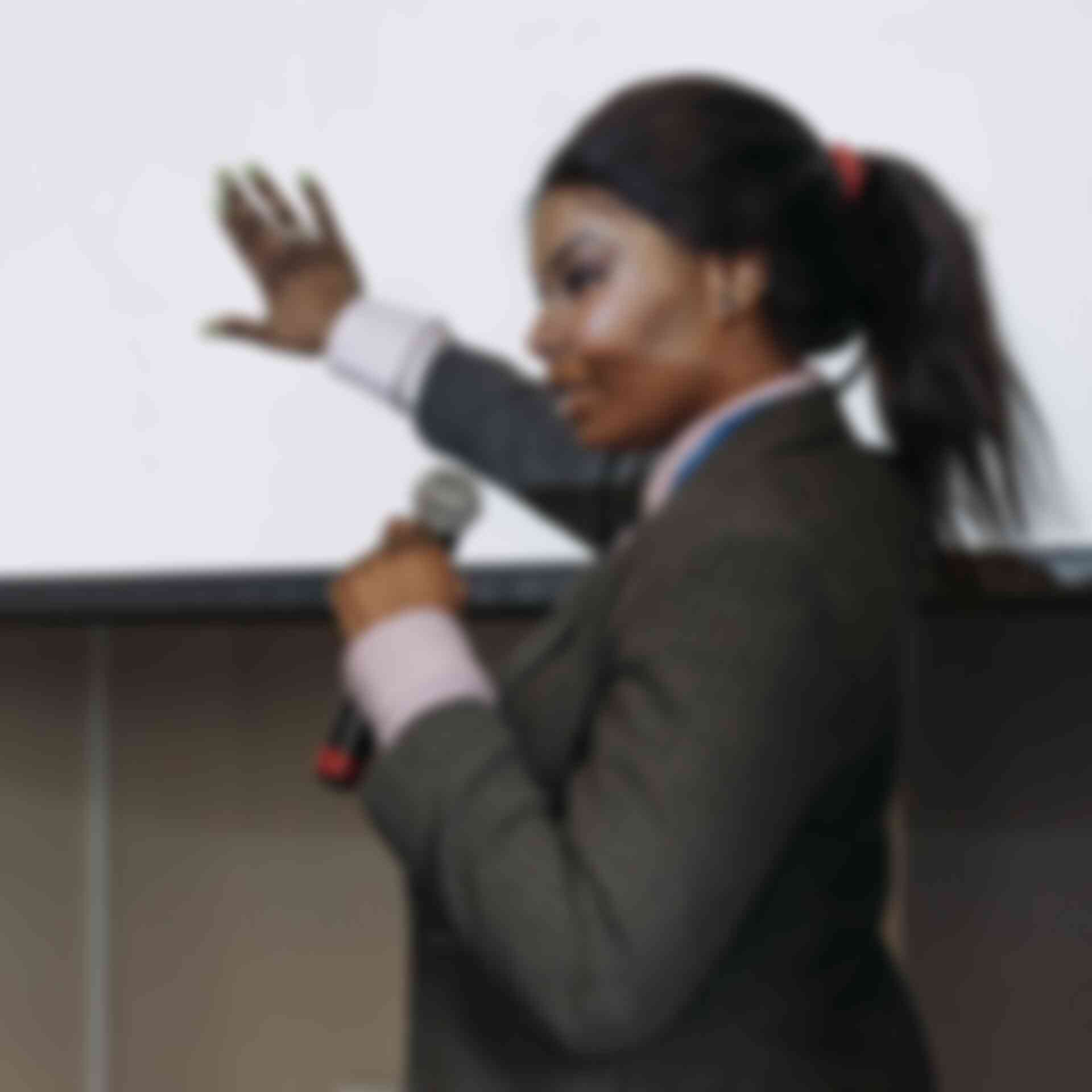 Delivering Compelling Presentations - woman-with-microphone-pointing-at-projecttion